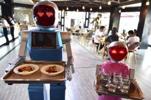 Robot couple Xiaolan (L) and Xiaotao carry trays of food at a restaurant in Jinhua, Zhejiang province, China, May 18, 2015. The restaurant, which opened on Monday has two robots delivering food for customers. The robots were designed as a couple, Xiaolan and Xiaotao, according to local media. REUTERS/Stringer CHINA OUT. NO COMMERCIAL OR EDITORIAL SALES IN CHINA - RTX1DGH4